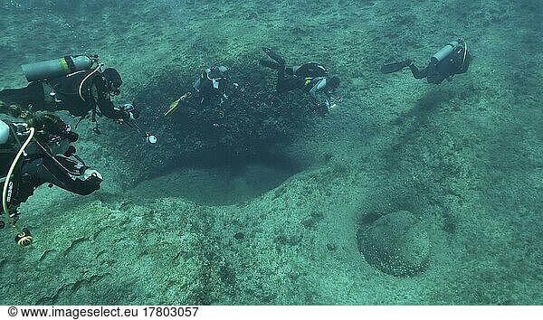 Group of scuba divers swims in the blue water above rocky seabed. Mediterranean Sea  Cyprus  Europe
