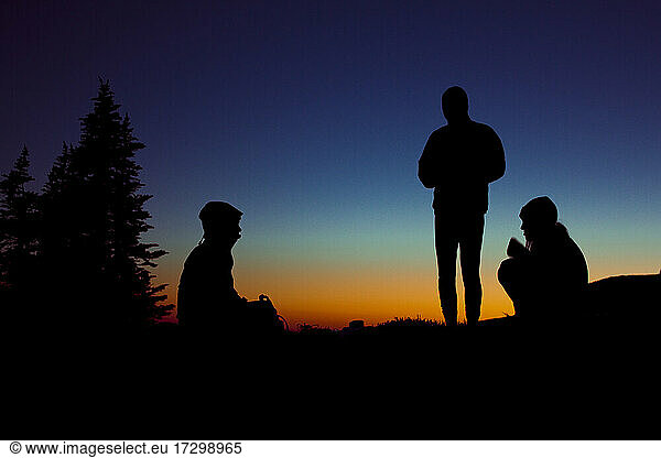 Group of three people enjoy an evening while camping in the mountains