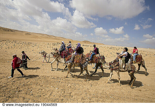 Group of tourists riding camels in the Egyptian desert near Giza
