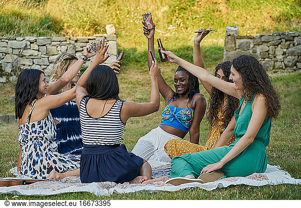 Group of women friends drinking beer and raising their smartphones