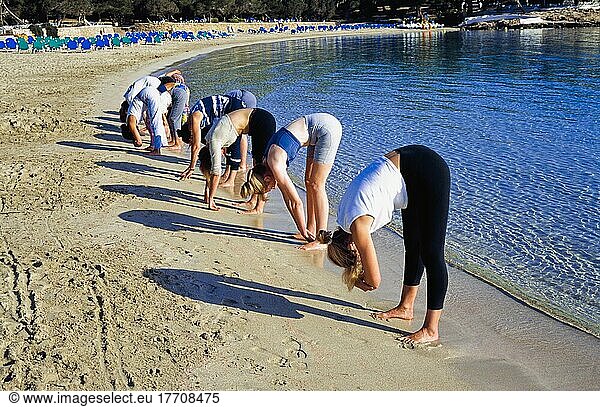 Group Of Women Performing Yoga On Beach