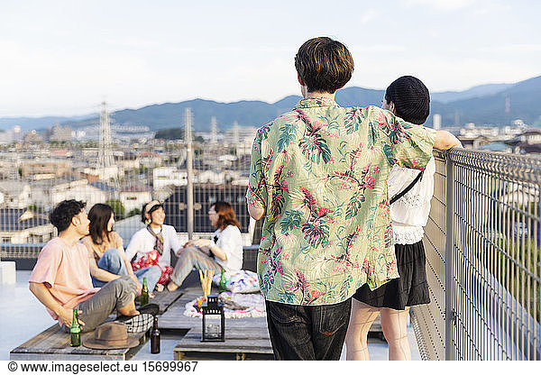 Group of young Japanese men and women on a rooftop in an urban setting.