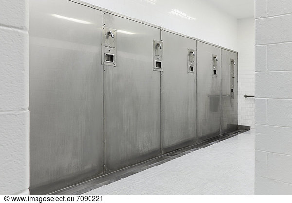Group shower facilities at a Correctional Facility. rows of showerheads on a wall. Wet room.