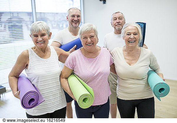 Gruppe glücklicher Senioren mit Matten für den Yoga-Kurs