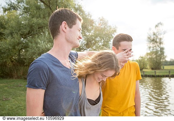 Gruppe junger Erwachsener  am See stehend  herumalbernd  lachend