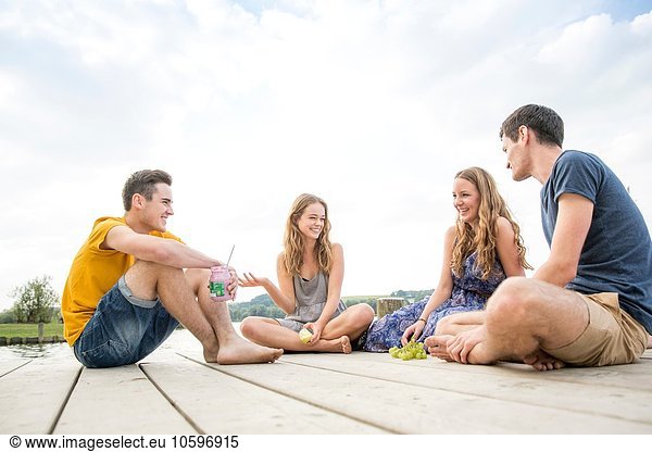 Gruppe junger Erwachsener am Steg sitzend  entspannend