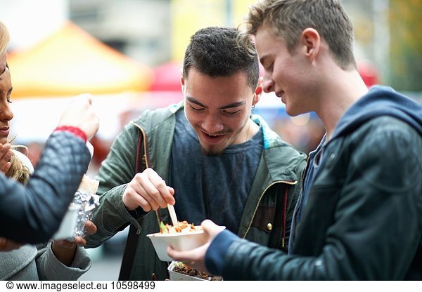 Gruppe junger Erwachsener beim Essen zum Mitnehmen  im Freien