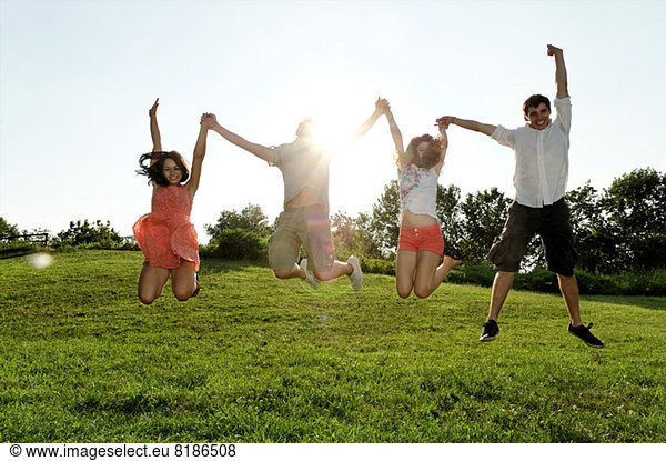 Gruppe junger Erwachsener  die mitten in der Luft springen.