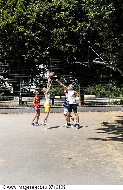 Gruppe von Freunden spielt Basketball auf dem Platz im Park