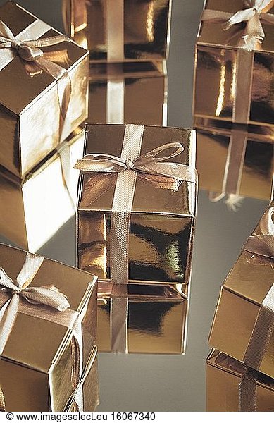 Gruppe von Gold funkelnden Geschenk-Boxen auf grauem Hintergrund mit Reflexion. Eine Reihe von Gold-Geschenk-Boxen für Geschenk  suprise  Geburtstag  Weihnachten Konzept Schönheit.