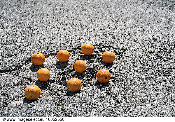Gruppe von Orangen in Asphaltrissen liegend #