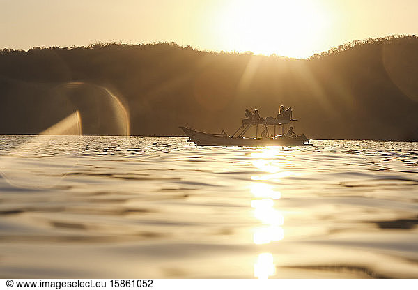 Gruppe von Personen auf dem Boot zur Zeit des Sonnenuntergangs