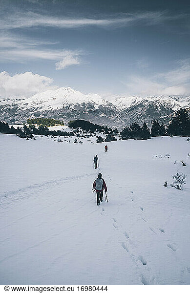 Gruppe von Wanderern auf einer verschneiten Hochebene vor schneebedeckten Gipfeln