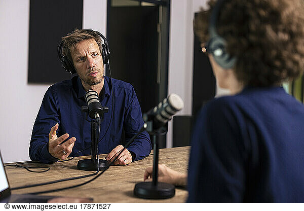 Guest wearing headset talking with presenter in radio station
