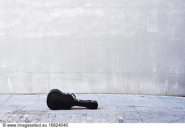 Guitar kept on road against concrete wall in city