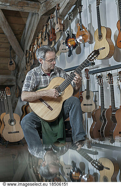 Guitar maker playing guitar in music store