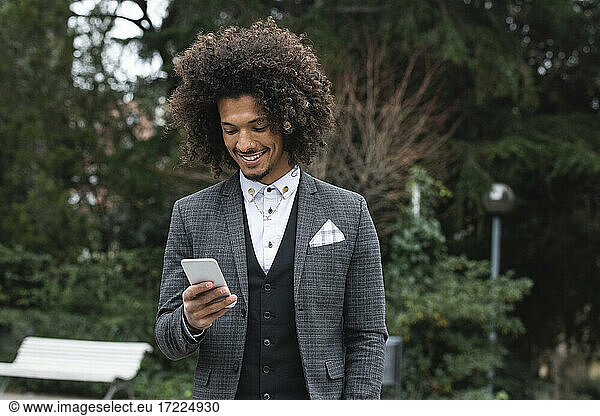 Gut aussehender  lächelnder Geschäftsmann  der ein Mobiltelefon benutzt