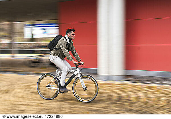 Gut aussehender Mann fährt Fahrrad an roter Wand