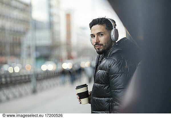 Gut aussehender Mann mit Kopfhörern und Kaffeetasse