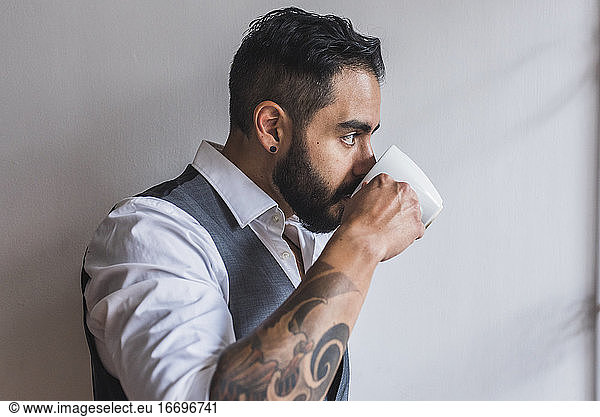 Gutaussehender Mann  gekleidet als Manager  trinkt Kaffee