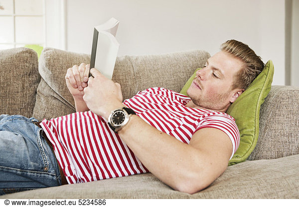 Guy reading book in sofa