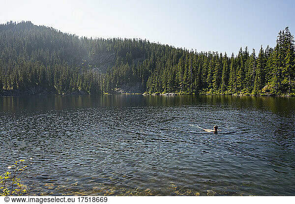 Guy swimming in an alpine lake during summer