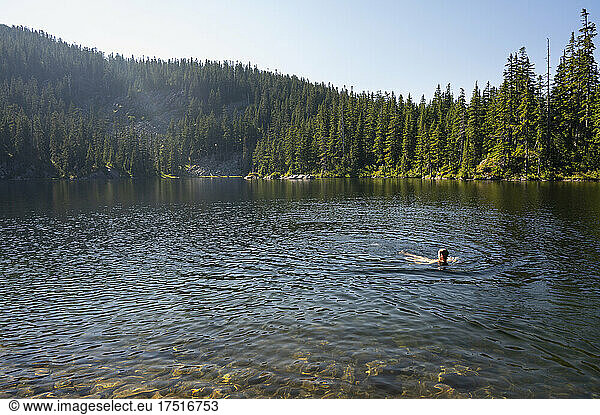 Guy swimming in an alpine lake during the hot summer