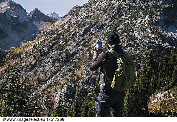 Guy taking photo with phone while hiking in the mountains