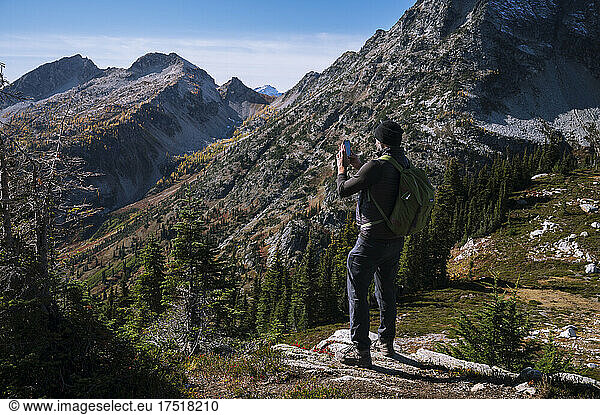 Guy taking photo with phone while hiking in the mountains