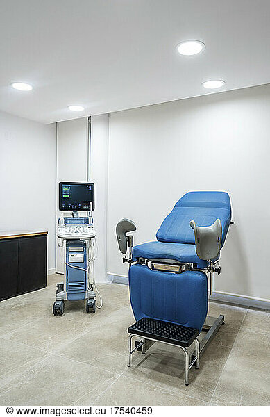 Gynaecologigal chair and medical scanner in illuminated ward