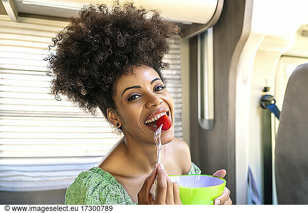Hübsche afrikanische Frau isst eine gesunde Erdbeere
