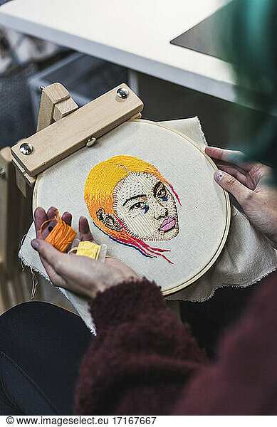 Hände einer jungen Frau  die im Atelier Fäden für eine Stickerei auswählt