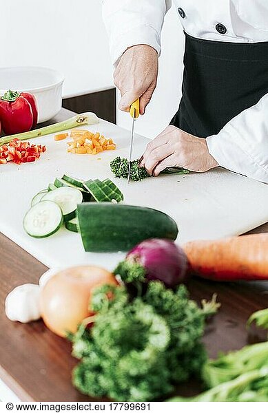 Hände einer Köchin beim schneidet Gemüse  Hände einer Köchin beim Zubereiten und schneidet Gemüse  Nahaufnahme einer Köchin beim schneidet Gemüse