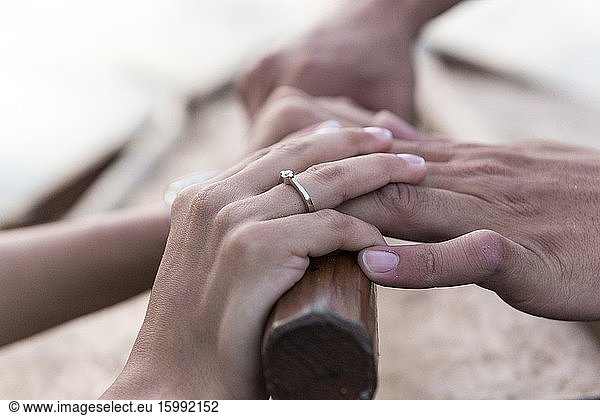 Hände eines Hochzeitspaares beim Binden der Tücher am Bug eines Bootes in der Albufera de Valencia bei Sonnenuntergang  Spanien