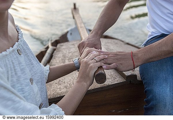 Hände eines Hochzeitspaares beim Binden der Tücher am Bug eines Bootes in der Albufera de Valencia bei Sonnenuntergang  Spanien