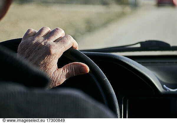 Hände eines älteren Mannes  der das Lenkrad eines Fahrzeugs hält