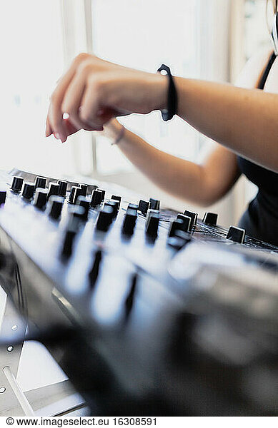 Hände eines weiblichen Club-DJs beim Abmischen von Ton im Aufnahmestudio