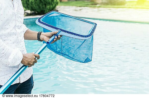 Hände halten einen Skimmer mit blauem Pool im Hintergrund. Ein Mann reinigt Pool mit Blatt Skimmer. Mann reinigt den Pool mit dem Skimmer  Person mit Skimmer Reinigung Pool