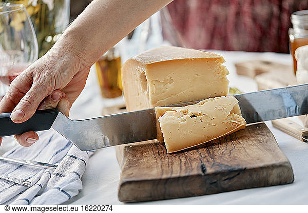 Hände schneiden Käse auf Holz