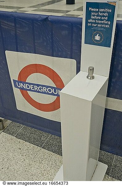 Händedesinfektionsgel in einer Londoner U-Bahn-Station mit Schildern  die aufgrund der Coronavirus-/Covid-19-Pandemie in London  England  Vereinigtes Königreich  auf einen sicheren sozialen Abstand hinweisen.