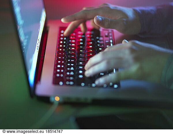 Hacker typing on illuminated laptop keyboard at office