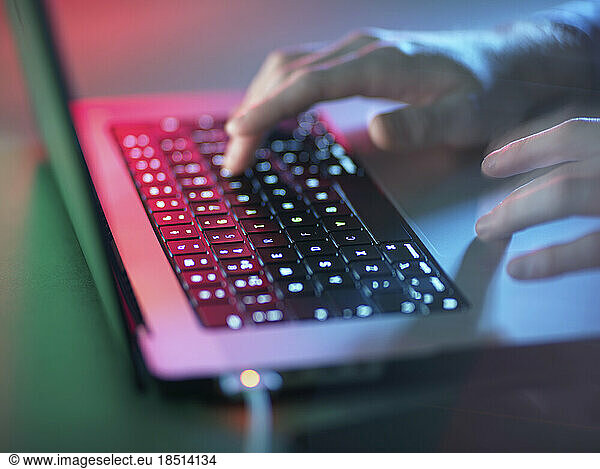 Hacker working on illuminated laptop at office