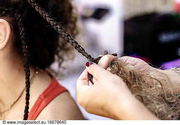 Hairdresser making braids to a young client at Hairdresser salon