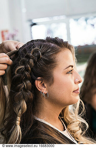 Hairdresser making braids to a young client at Hairdresser salon