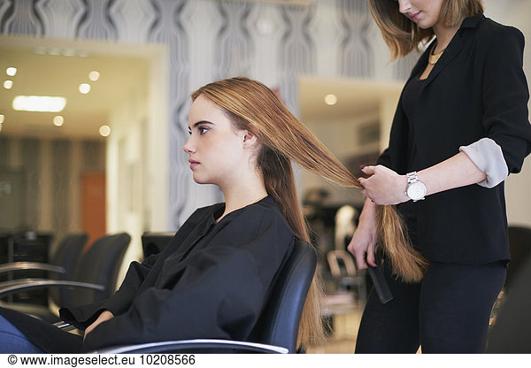 Hairdresser preparing to cut customer’s long hair in salon