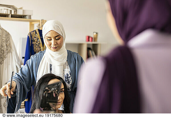 Hairdresser styling bride's hair for wedding in boutique