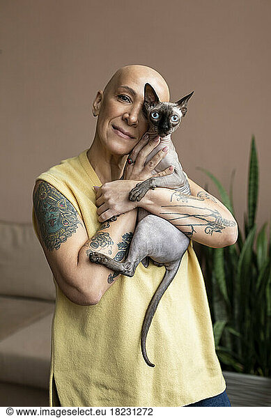 Hairless woman holding Sphynx cat in her arms