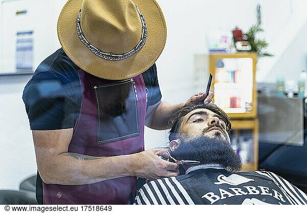 Hairstylist serving client at barber shop.