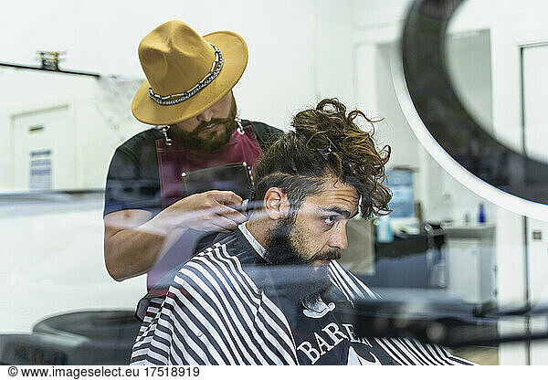 Hairstylist serving client at barber shop.