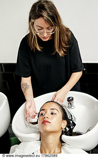 Hairstylist Washing Hair Of Client Over Sink